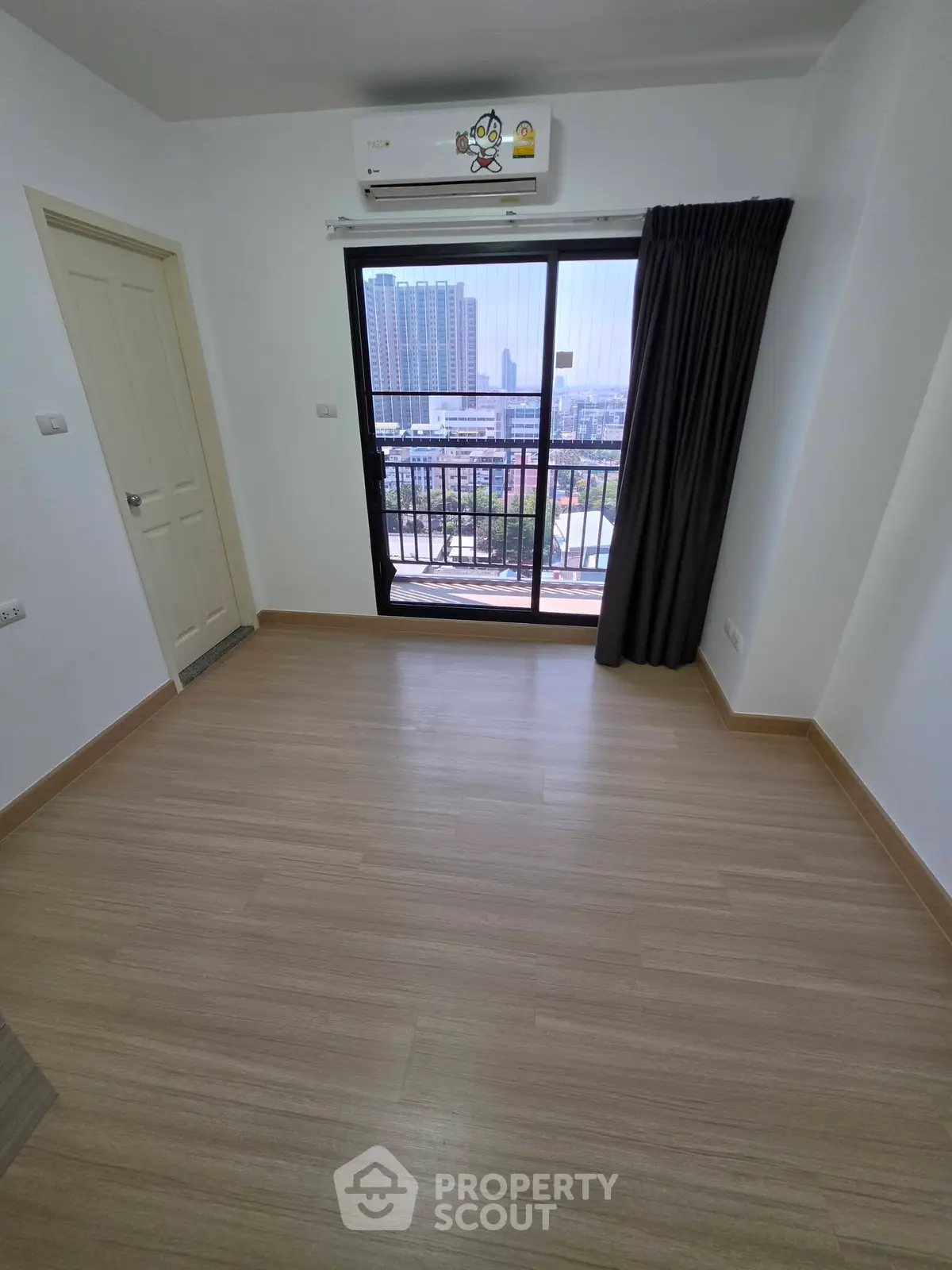 Bright empty room with wooden flooring and balcony view in modern apartment.