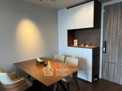 Modern dining area with sleek wooden table and built-in storage cabinets.