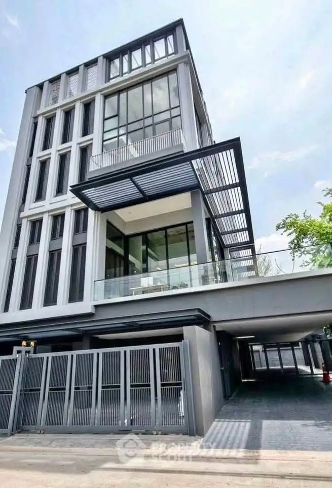 Modern multi-story building with sleek design and large windows, featuring a spacious carport and contemporary facade.