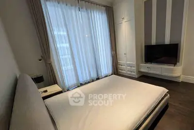 Modern bedroom with large window and built-in storage, featuring a sleek TV setup.