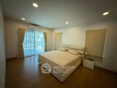 Spacious bedroom with large windows and elegant curtains, featuring a comfortable bed and modern decor.