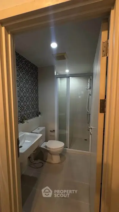 Modern bathroom with stylish tile accent wall and glass shower enclosure