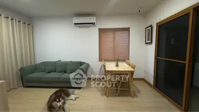 Cozy living room with green sofa, dining table, and air conditioning