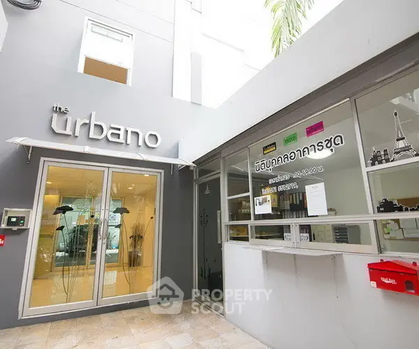 Modern building entrance with glass doors and stylish signage at The Urbano.