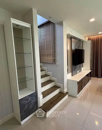 Modern living room with sleek TV unit and stylish staircase design