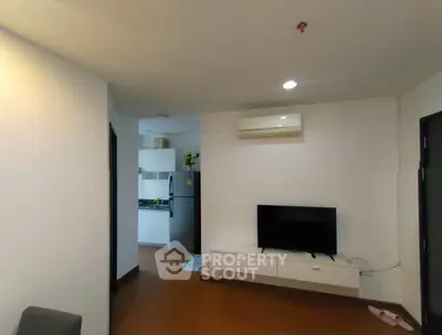 Modern living room with wall-mounted TV and view into compact kitchen