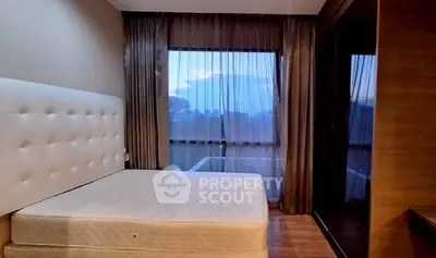 Cozy bedroom with large window and elegant curtains, offering serene views and natural light.