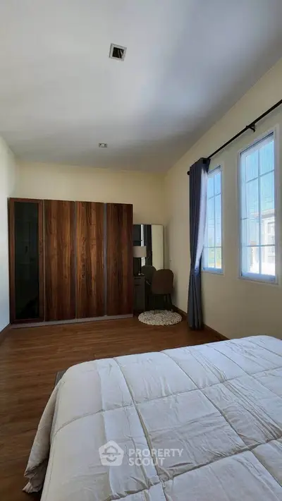 Spacious bedroom with wooden wardrobe and natural light
