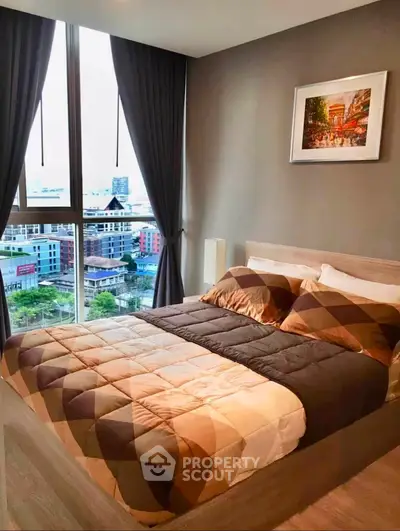Modern bedroom with large window offering city view, stylish decor, and cozy bedding.