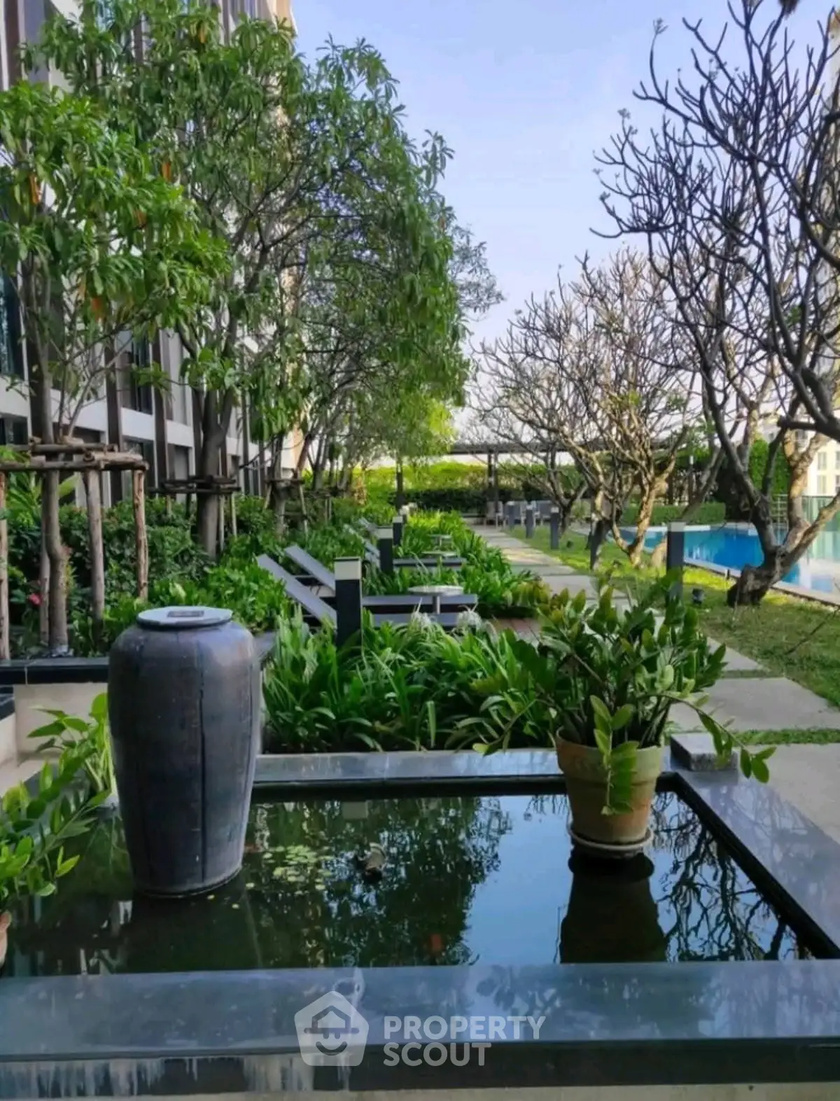 Luxurious garden view with serene water feature and lush greenery in modern residential complex.