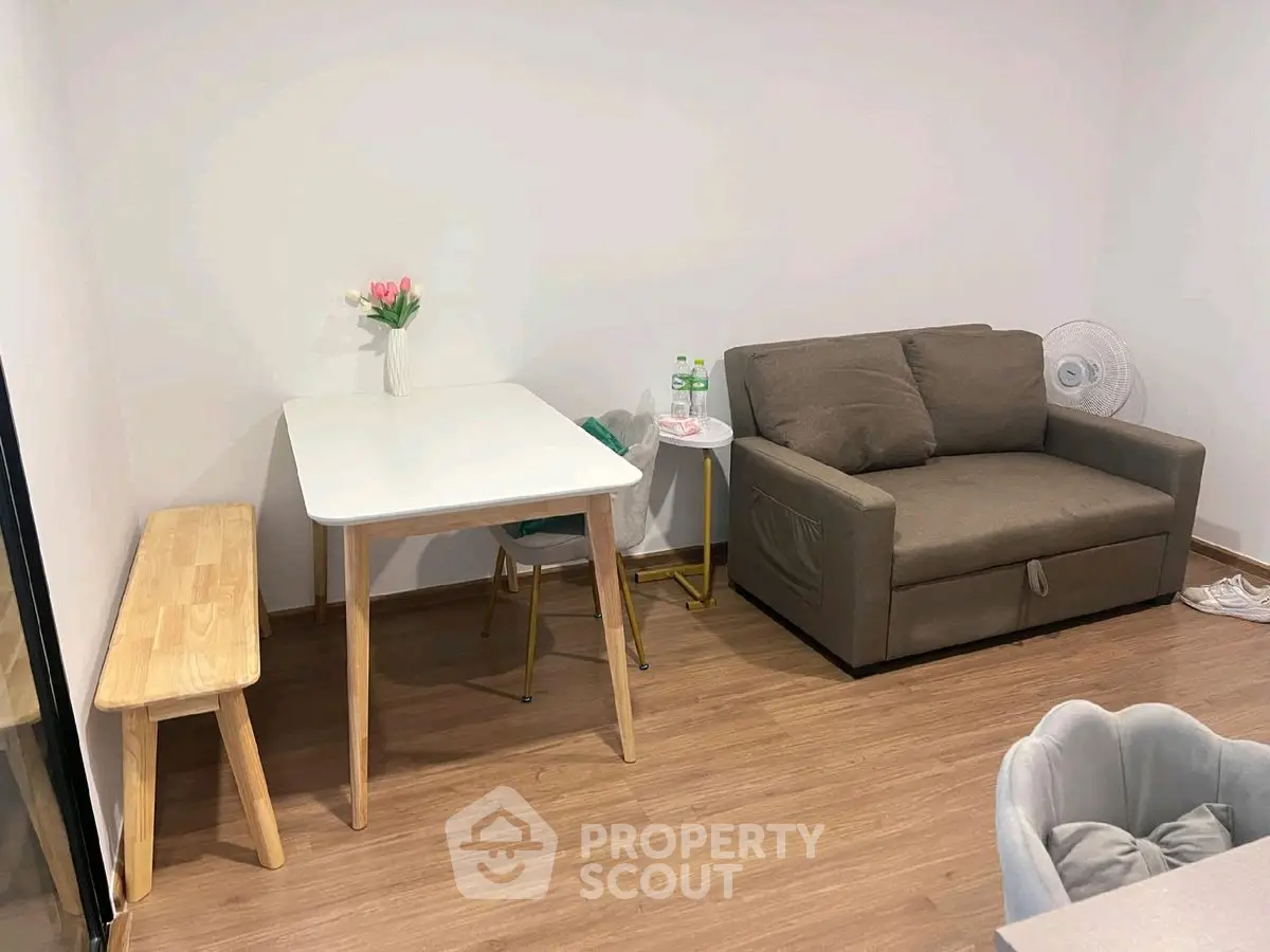 Cozy living room with modern sofa and dining table, perfect for small spaces.