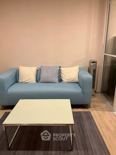 Cozy living room with modern blue sofa and sleek coffee table on a stylish rug.