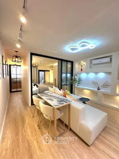 Modern living room with stylish lighting and open layout, featuring a cozy dining area and elegant decor.