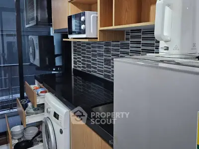 Modern kitchen with sleek black countertops and built-in appliances in a compact layout.