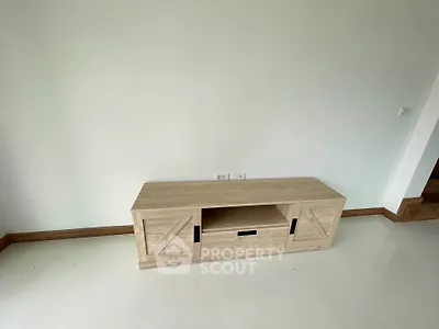 Minimalist wooden TV stand in a bright, unfurnished room with white walls and floor.
