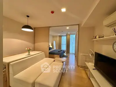 Modern open-plan living room with cozy dining area and stylish bedroom view.