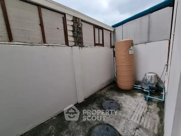 Outdoor utility area with water tank and drainage system