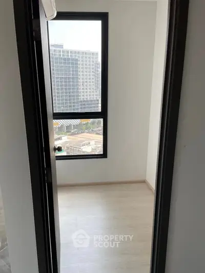 Bright room with large window offering city view in modern apartment.