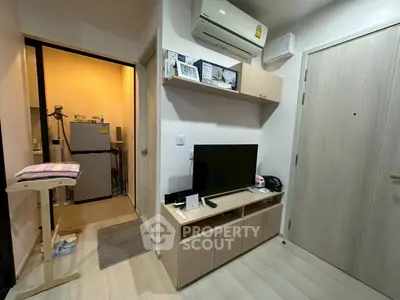 Cozy apartment interior with modern TV setup and compact kitchen area.