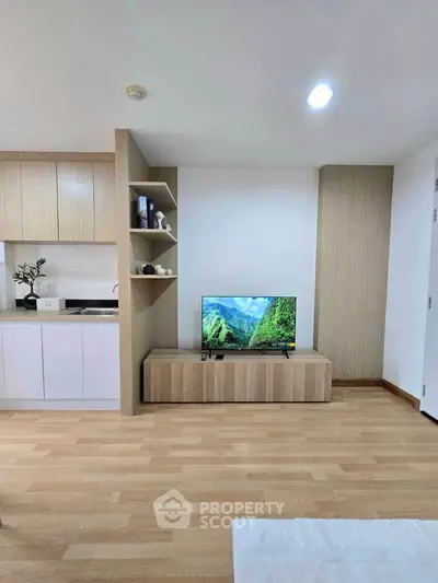 Modern living room with wooden flooring and built-in TV cabinet in stylish apartment.