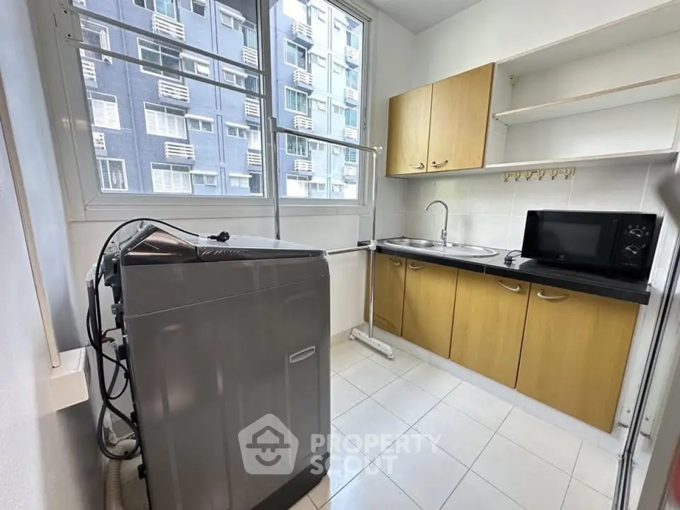Modern kitchen with washing machine and microwave in high-rise apartment