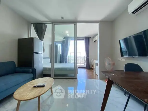 Modern living room with open layout and balcony view, featuring sleek furniture and natural light.