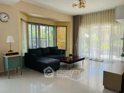 Spacious living room with large windows and modern furniture, offering a bright and inviting atmosphere.