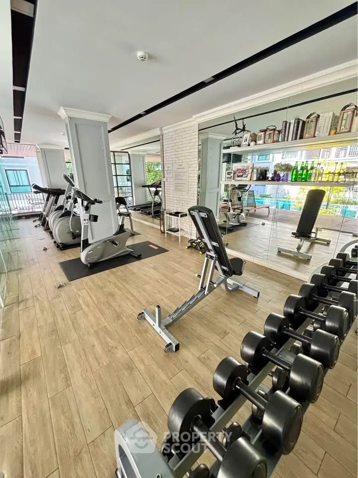 Modern gym with state-of-the-art equipment and mirrored walls in luxury residential complex.