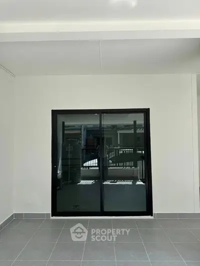 Spacious modern balcony with sleek sliding glass doors and tiled flooring.