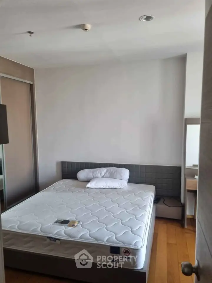 Cozy bedroom with modern design and wooden flooring, featuring a comfortable bed and ample natural light.