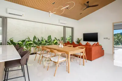 Modern open-plan living room with stylish dining area and lush greenery view.