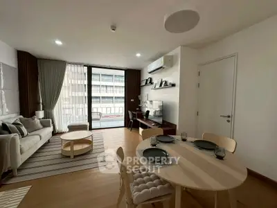 Modern living room with dining area, featuring stylish furniture and large windows for natural light.