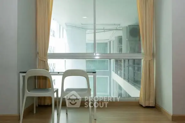 Bright study area with large window and modern furniture in high-rise apartment.