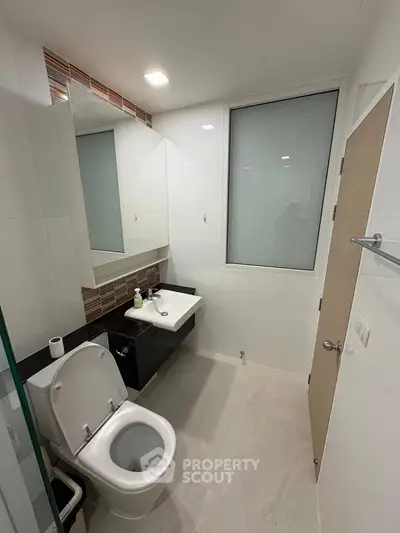 Modern bathroom with sleek fixtures and large mirror in a contemporary apartment.