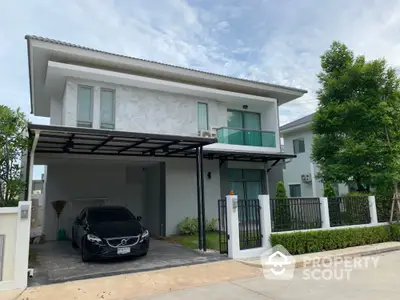 Modern two-story house with carport and lush greenery in a serene neighborhood.