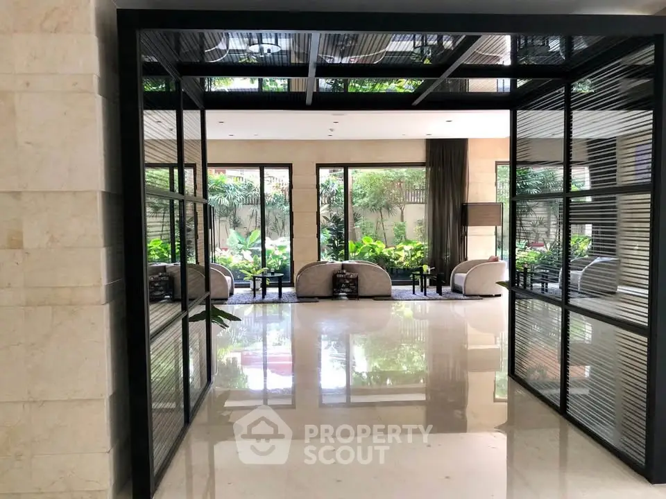 Luxurious lobby with modern glass doors and lush garden view, perfect for upscale living.
