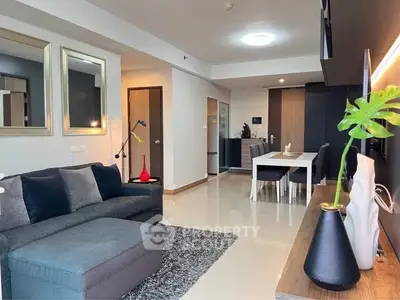 Modern living room with stylish decor and open dining area, featuring sleek furniture and ambient lighting.
