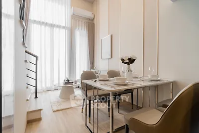 Modern dining area with elegant table setting and natural light in a stylish apartment.