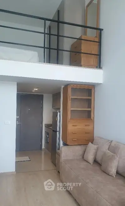 Modern loft apartment with mezzanine, cozy sofa, and compact kitchen area.