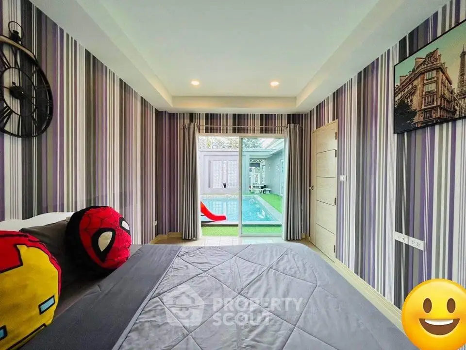 Charming bedroom with direct pool access, adorned with playful superhero cushions and stylish striped wallpaper, perfect for modern living.