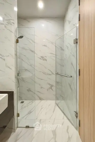 Luxurious modern bathroom with elegant marble tiles and glass shower enclosure.