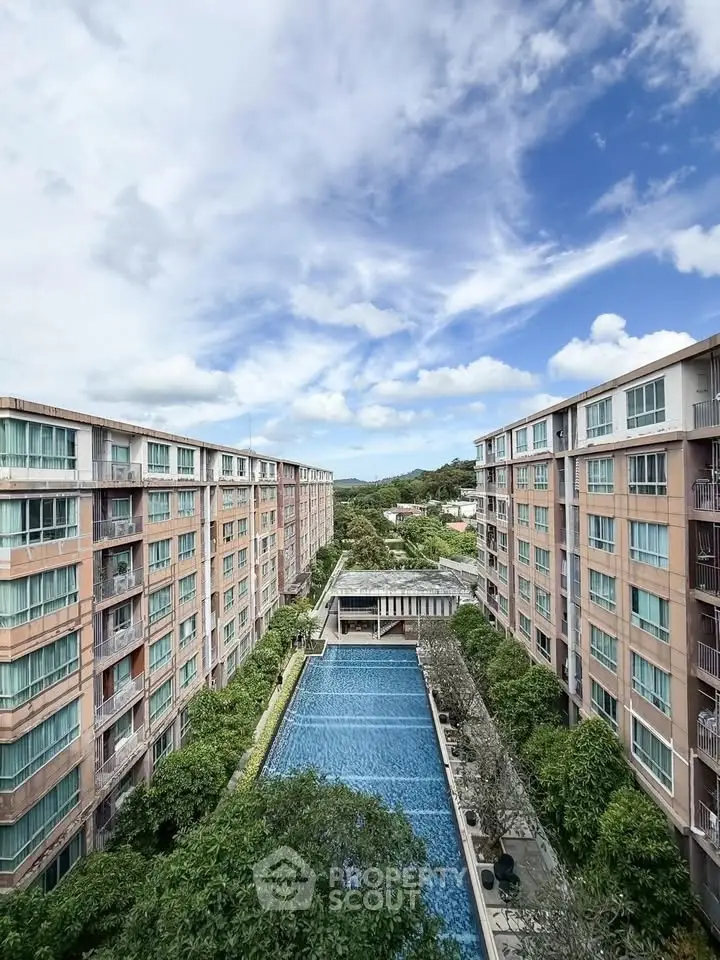 Stunning aerial view of modern apartment complex with central swimming pool and lush greenery.