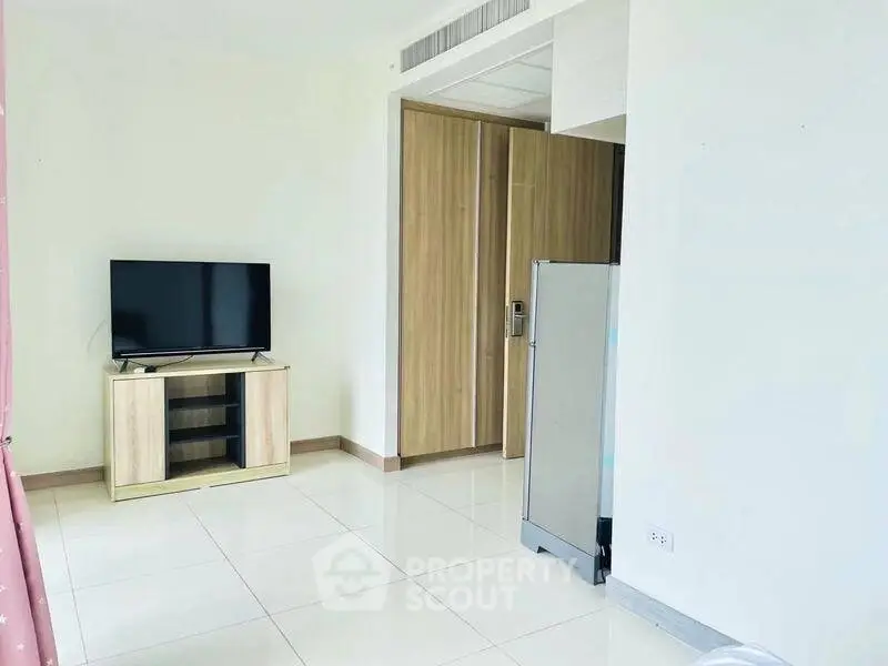 Modern living room with TV and sleek wooden furniture in bright apartment.