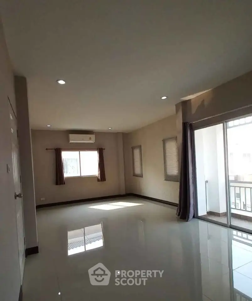 Spacious empty living room with large windows and balcony access, perfect for customization.