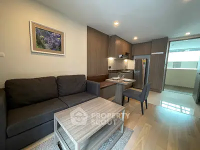 Modern living room with cozy seating and sleek kitchen in open layout apartment.
