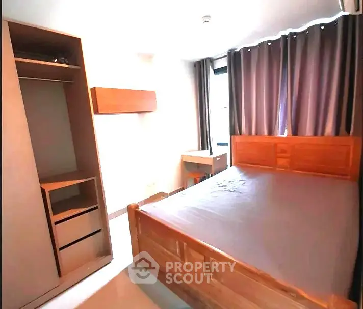 Cozy bedroom with wooden furniture and large window with curtains.