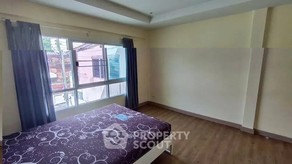 Spacious bedroom with large window and wooden flooring, ideal for natural light lovers.