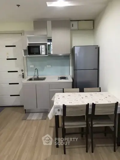 Modern kitchen with dining area, featuring sleek cabinetry, stainless steel appliances, and cozy dining setup.