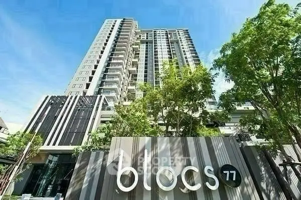 Modern high-rise building with lush greenery and clear blue sky