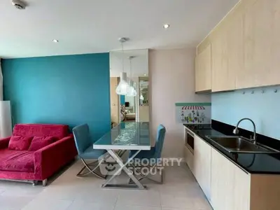 Modern open-layout kitchen and living room with vibrant decor and sleek furnishings.